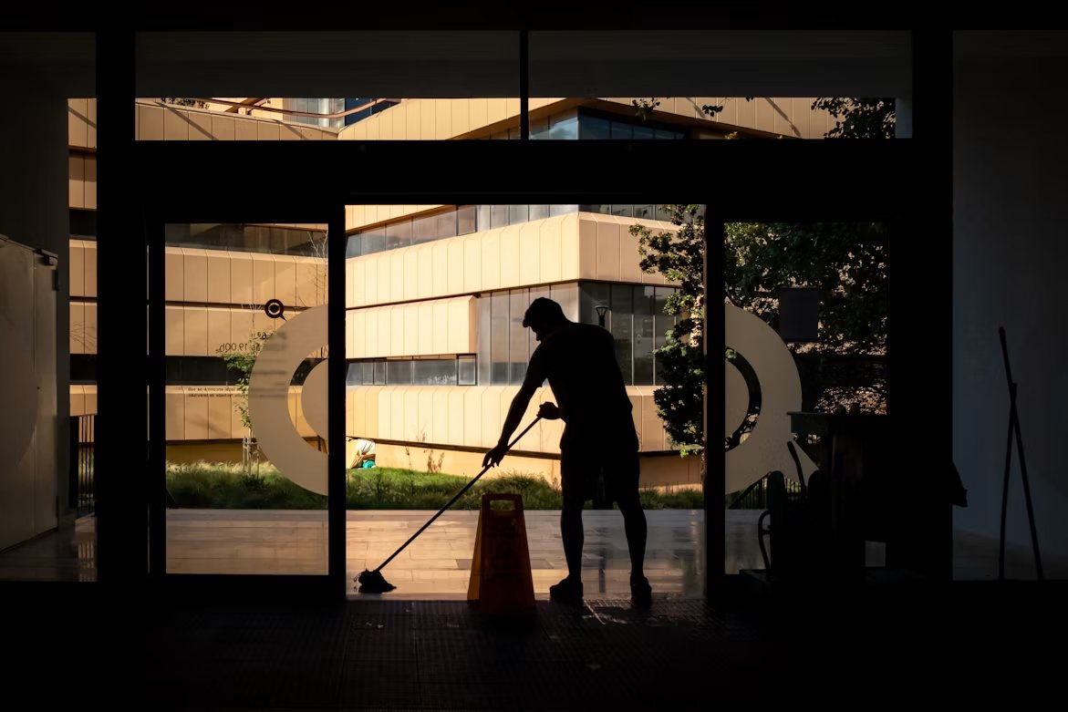 A facility cleaner at work in a commercial building at dusk