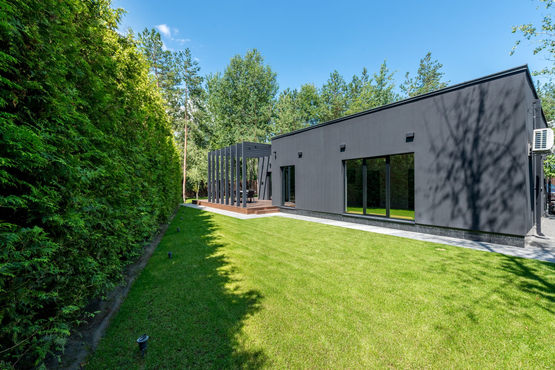 Modern gray house with a sharply manicured backyard lawn and landscaping